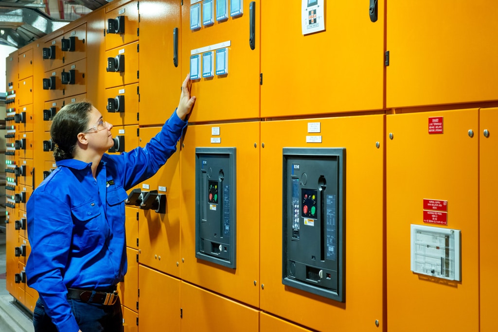 GSTEC Electrical technician inspecting critical power systems and industrial switchboards in a commercial plant room.