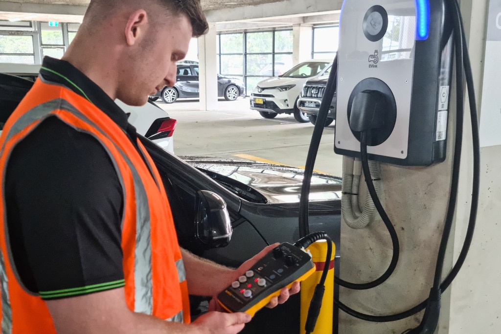 GSTEC technician Electrician testing and commissioning an EV charging station in a commercial underground car park.
